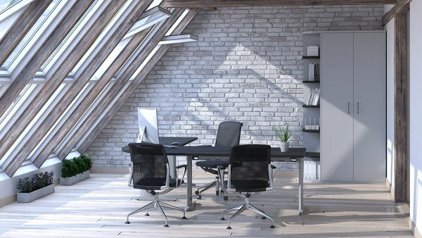 Oficina bajo techo abuhardillado con escritorio ergonómico negro, sillas de oficina modernas, almacenamiento integrado blanco y pared de ladrillo expuesto, combinando elementos rústicos y modernos para un diseño de oficina eficiente.